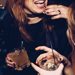two people holding cocktails and laughing